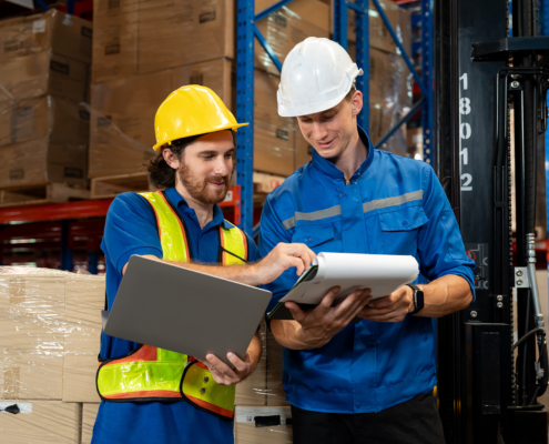 Male Warehouse Staff And Supervisor Reviewing Logistics Documents